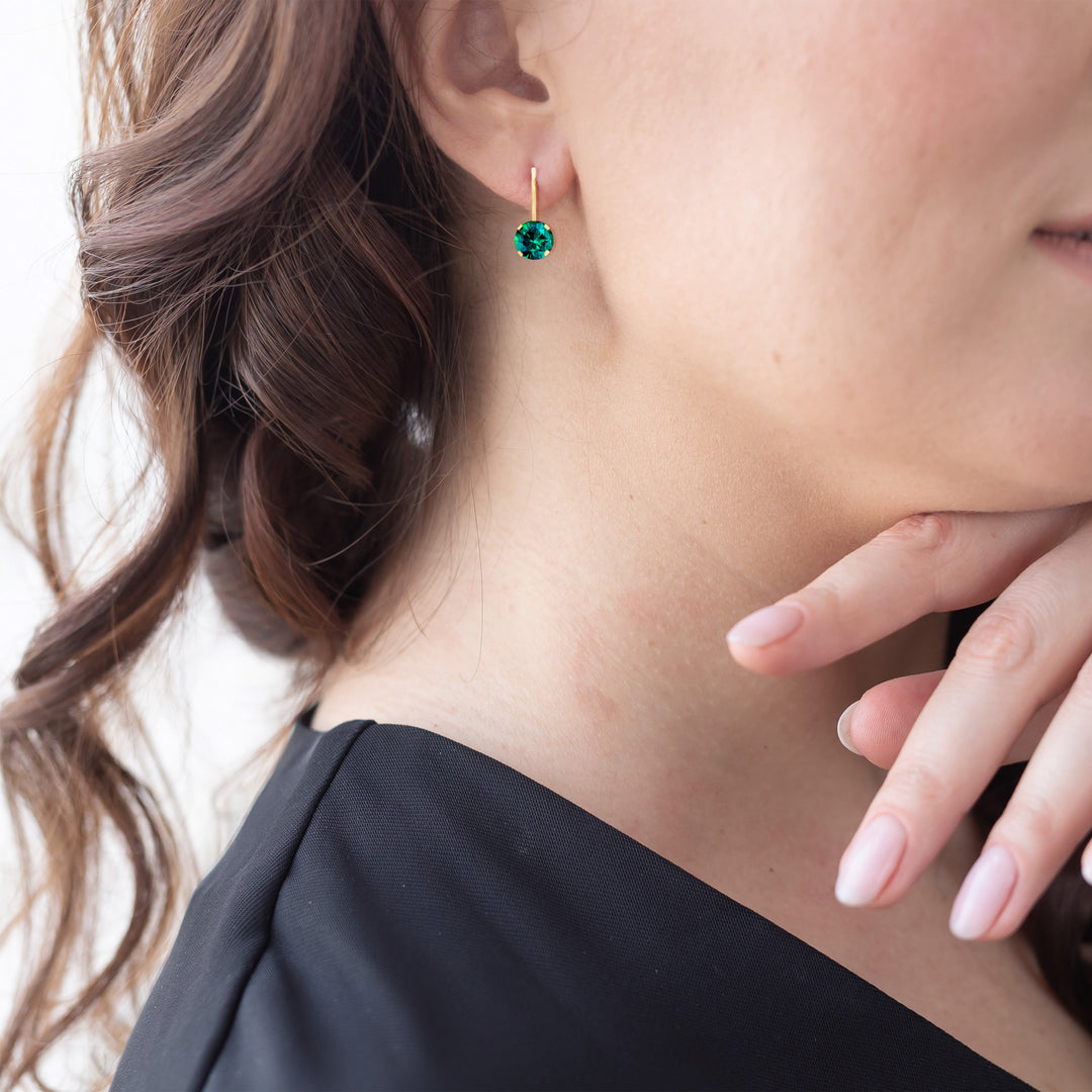 14K yellow gold lab-grown emerald leverback earring on model, hand near collarbone shows natural size reference
