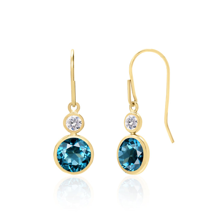 Dainty drop earrings with 6mm round-shaped London blue topaz stones and white topaz accents, set in 14K white or yellow gold. Choose between ear wire or lever back closure. Ideal as December birthstone or 4th-anniversary gift